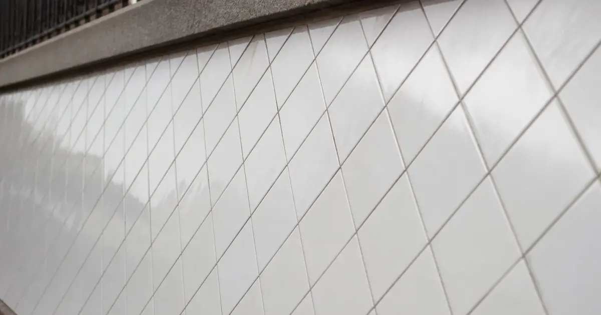 Carreaux blancs alignes en motif diagonal sur surface murale inclinee