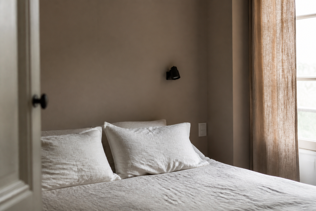 Chambre avec mur taupe, linge lin blanc, rideaux naturels