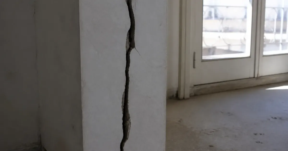 Fissure verticale profonde traversant mur beton porteur immeuble