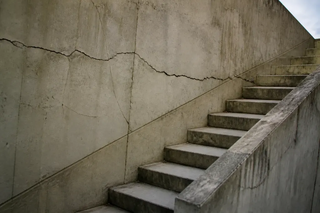 Fissures murales escalier et diagonales sur facade beton