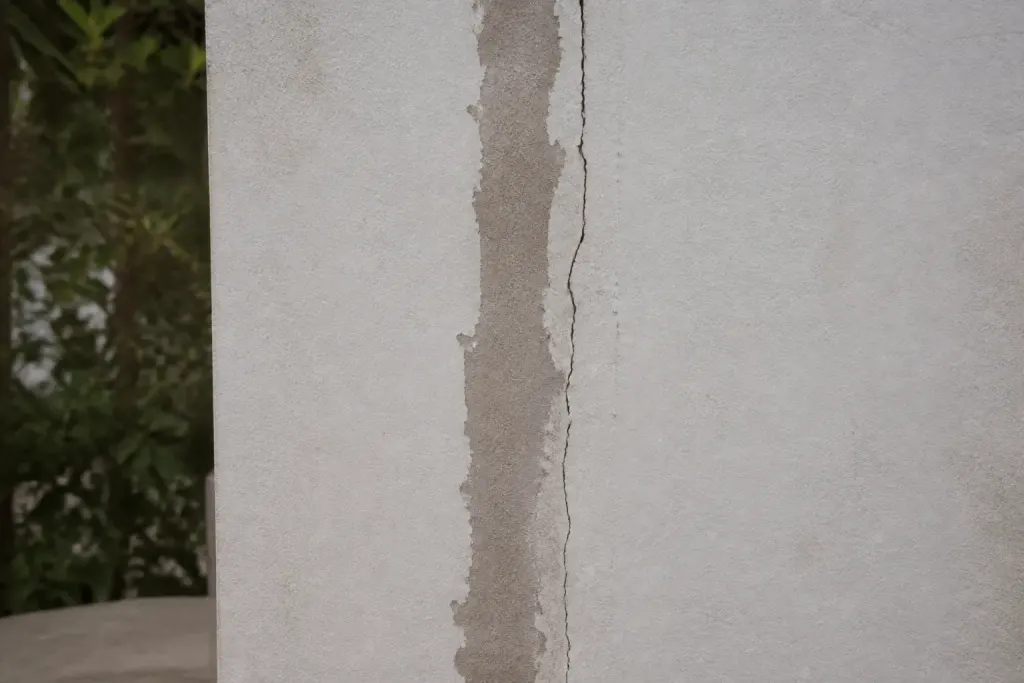 Mur blanc avec fissure verticale et enduit de reparation partiel