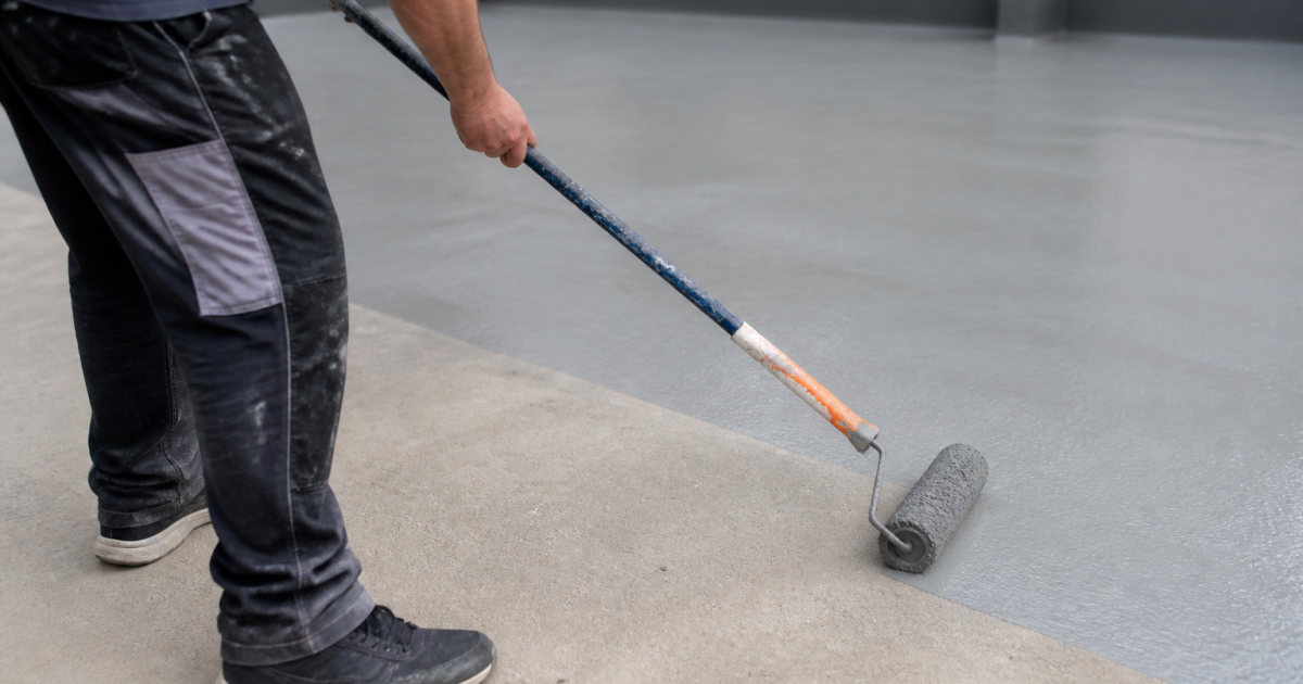 Personne peignant surface beton gris avec rouleau applicateur