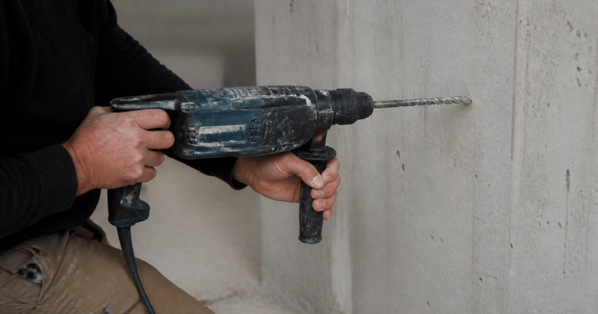 Perceuse tenue horizontalement contre paroi beton grise