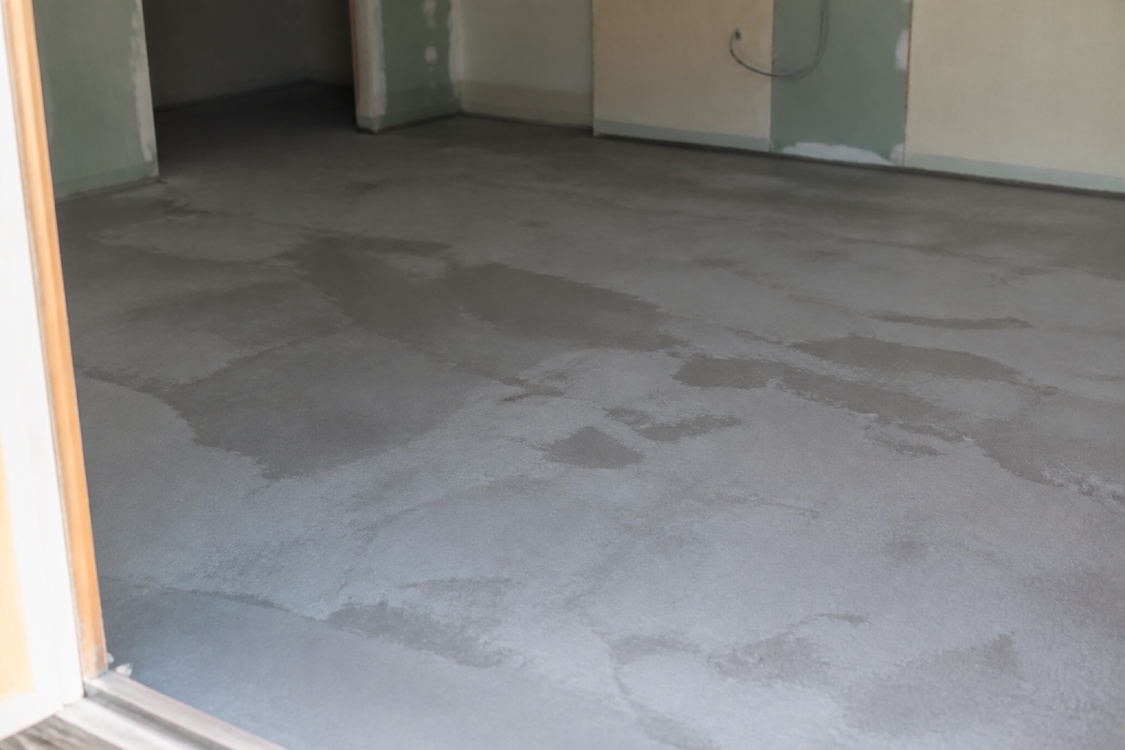 Surface de ragréage grise en cours de séchage avec traces d'humidité
