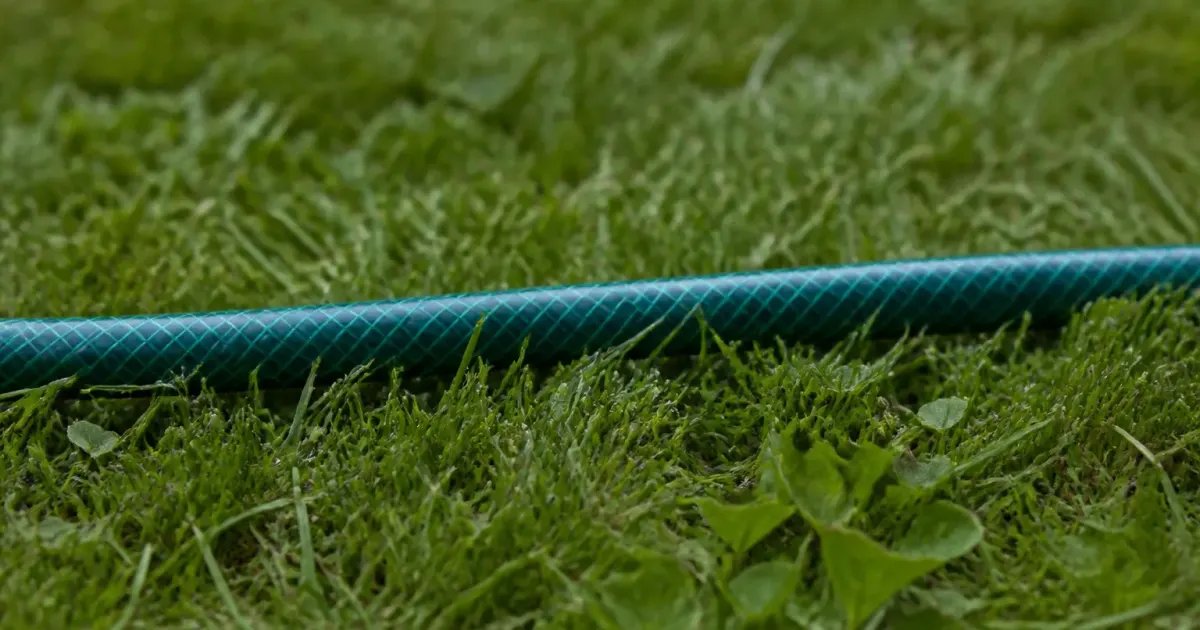 Tuyau d'arrosage posé horizontalement sur herbe verte